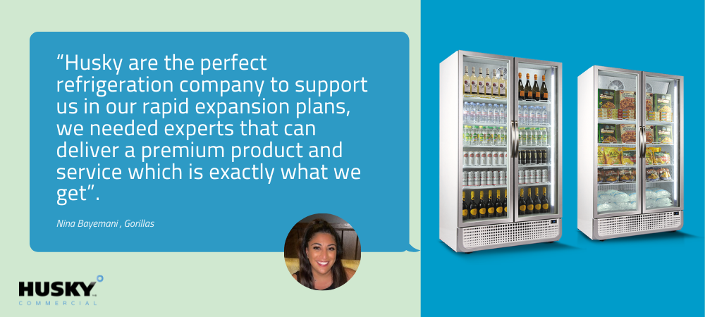 Testimonial text praising Husky refrigeration, attributed to Nina Baynesova from Gorillas, with her image. On the right, two commercial display refrigerators filled with drinks and food on a blue background. Text: "Husky are the perfect refrigeration company to support us in our rapid expansion plans, we needed experts that can deliver a premium product and service which is exactly what we get".