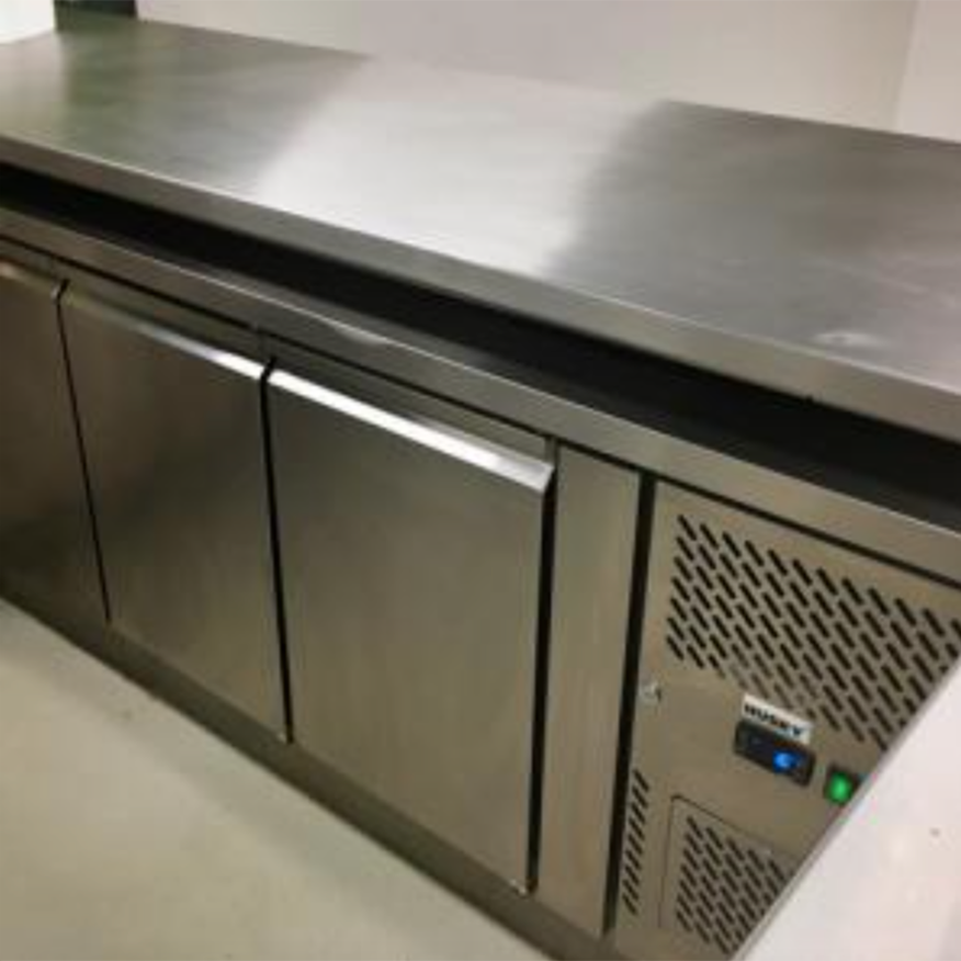 Stainless steel commercial refrigerator closed, placed in a kitchen environment with multiple storage doors and a vented side panel within a clean, sterile setting. No text present.