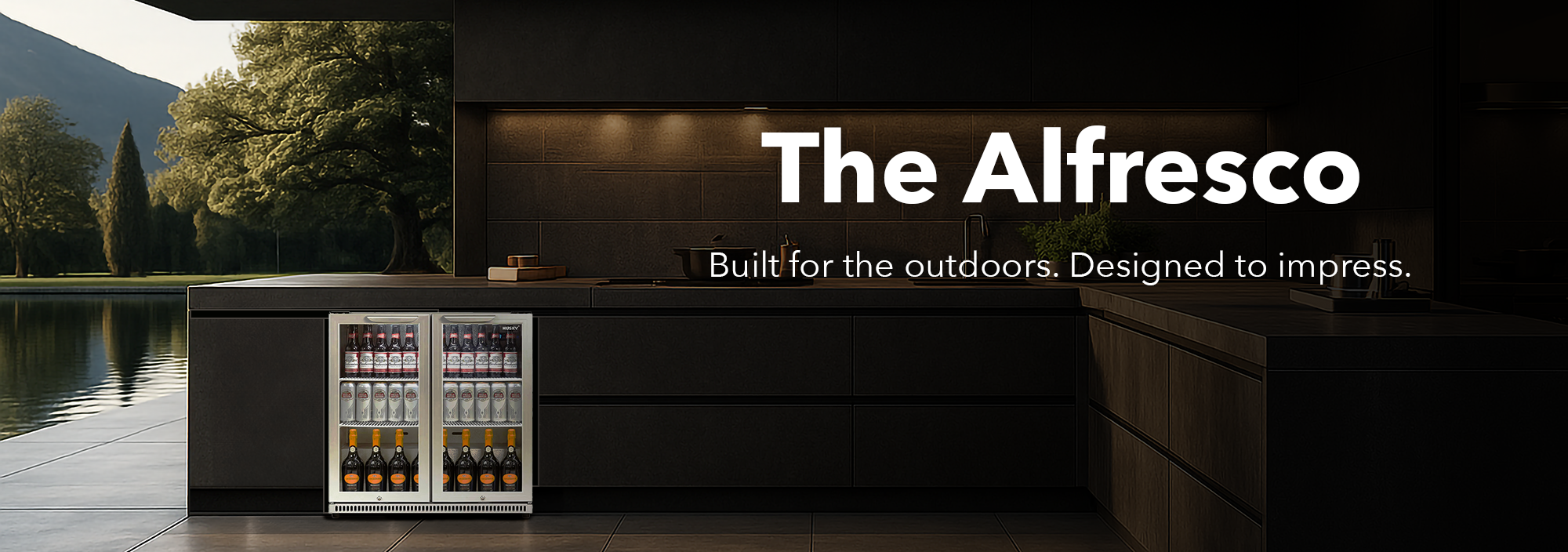 Sleek Husky “Alfresco” outdoor double-door beverage fridge built into a modern patio kitchen, fully stocked with bottles and cans against a scenic lakeside backdrop.