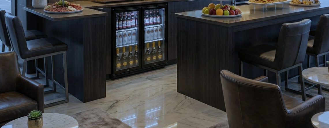 Drinks fridge built into a modern bar island, fully stocked with beverages and illuminated for premium display in a hospitality setting